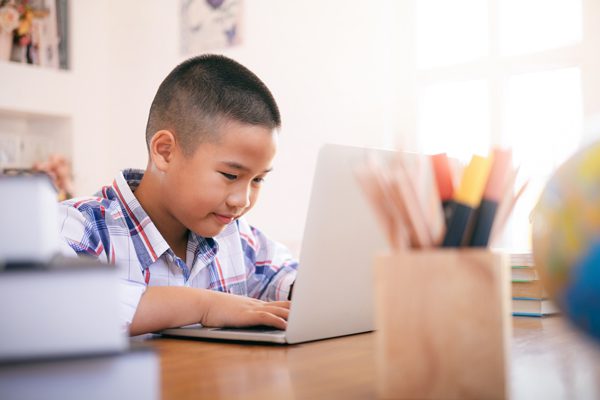 young boy doing schoolwork on laptop