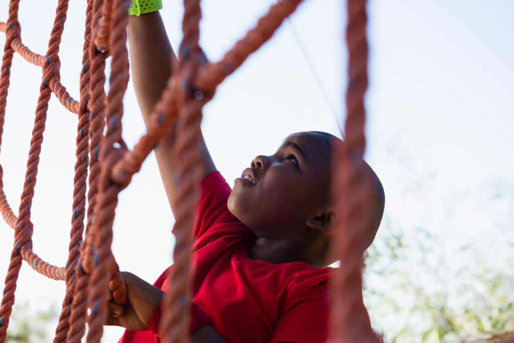Boy climbing a net during obstacle course training Boy climbing a net during obstacle course training